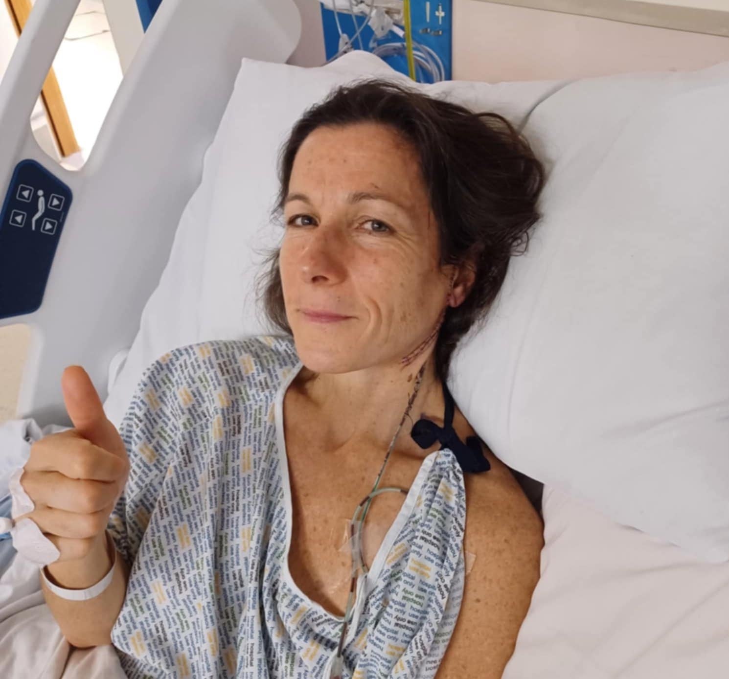Lisa giving thumbs up in hospital bed after surgery