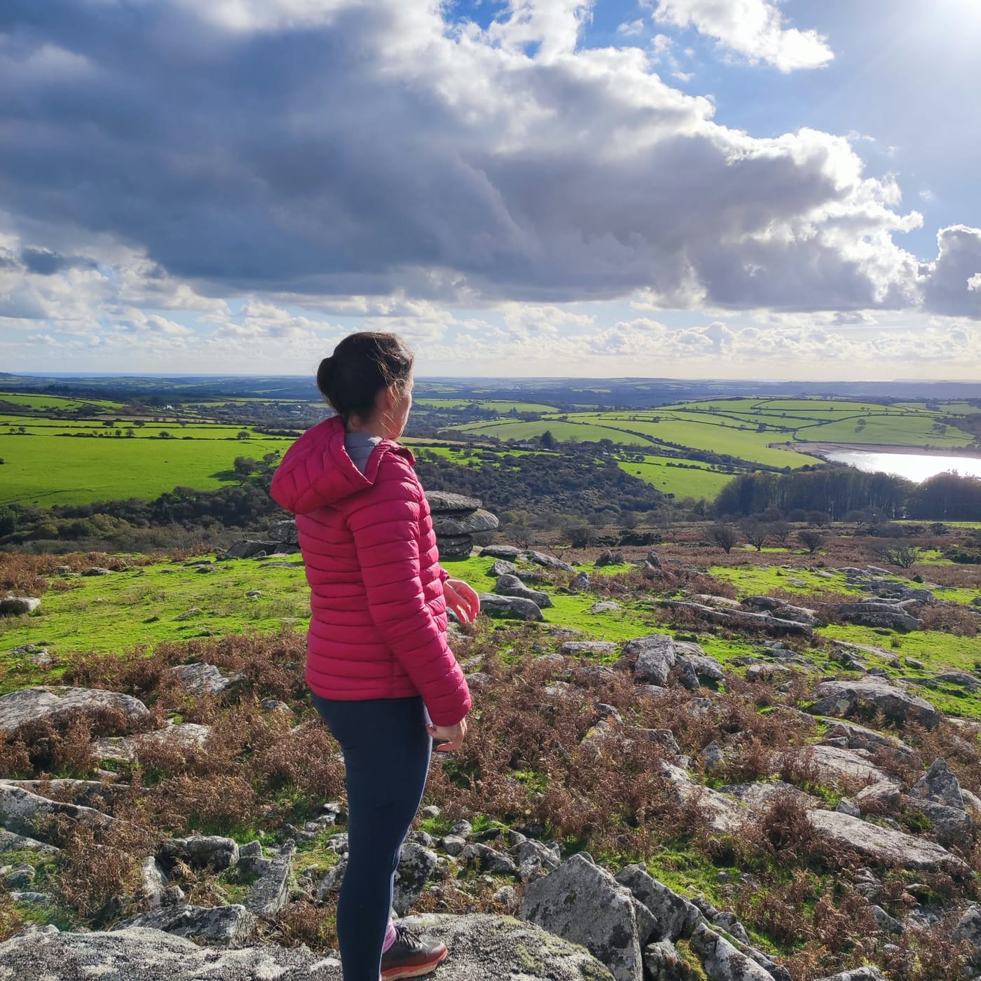Lisa looking out over the Cornish countryside from a granite tor